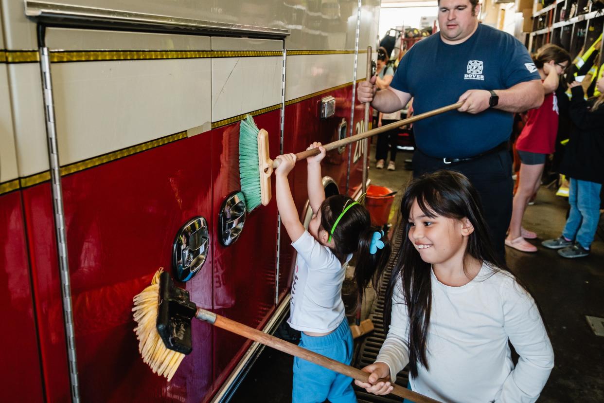 Ziola Goodall, 7, and her sister Tala, 3, help Dover firefighter Matt Hamsher wash a fire department squad in the bay of the downtown fire station, as part of the Dover Acts of Kindness project.