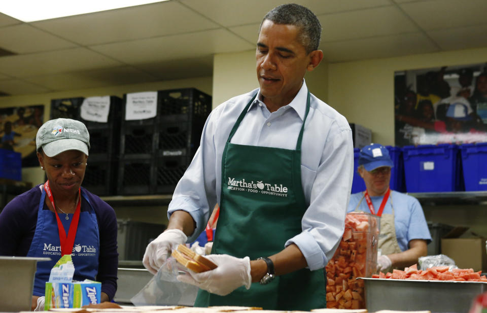 President Barack Obama stands with Chantelle Britton, who works at the Department of Health and Human Services, left, while putting a bologna sandwich into a Ziploc bag as he visits Martha's Table, which assists the poor and where furloughed federal employees are volunteering, in Washington, Monday, Oct. 14, 2013. (AP Photo/Charles Dharapak)