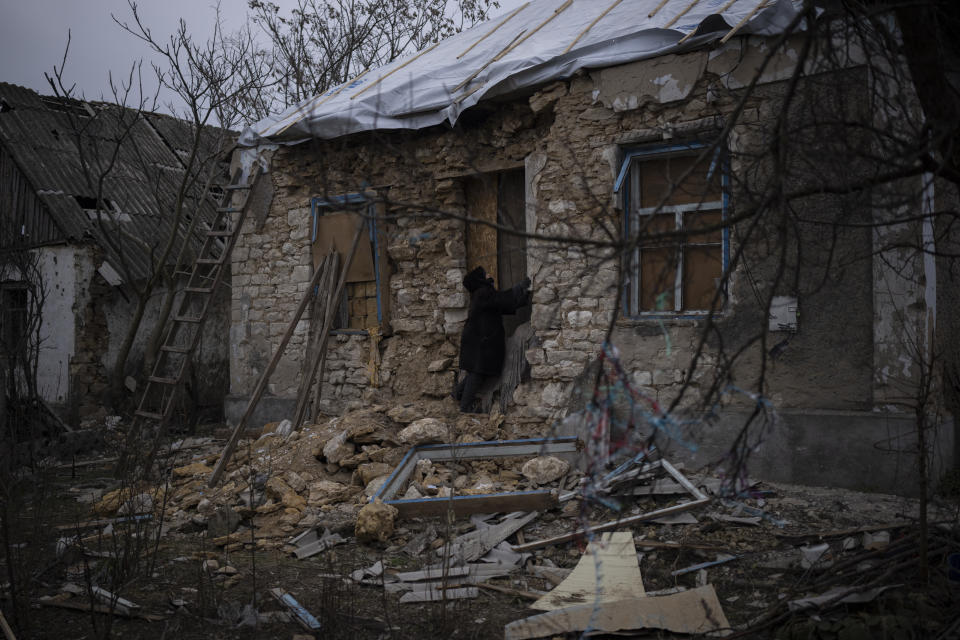 Oleksandra Hryhoryna inspecciona su casa, dañada por proyectiles el pasado otoño en Kalynivske, Ucrania, el sábado 28 de enero de 2023. (AP Foto/Daniel Cole)