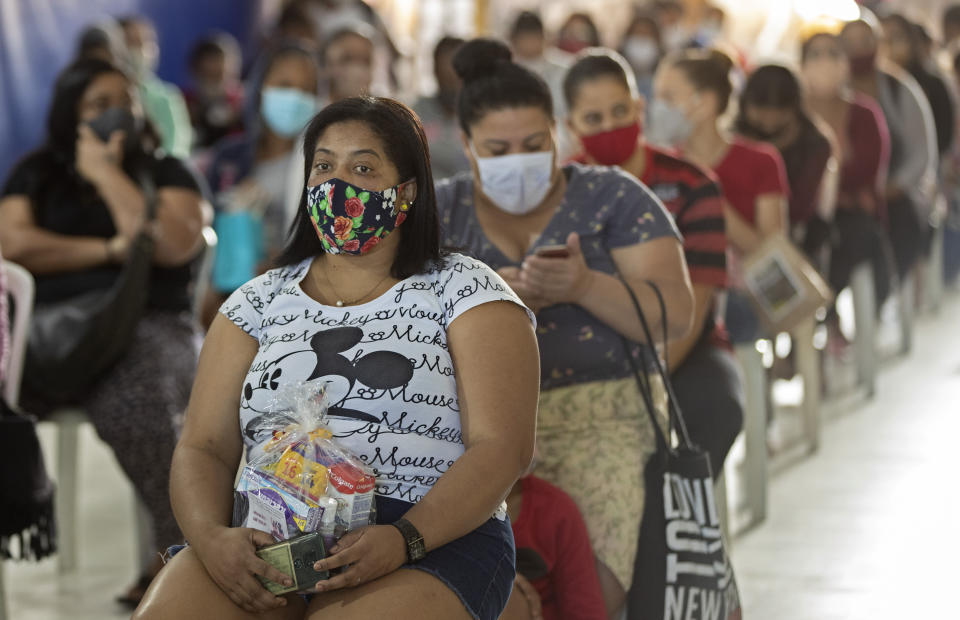 Women and girls sit after receiving a donation of sanitary napkins and other female hygiene supplies provided by the local NGO "G10 Favelas" amid the COVID-19 pandemic in the favela of Paraisopolis, in Sao Paulo, Brazil, Monday, May 24, 2021. (AP Photo/Andre Penner)