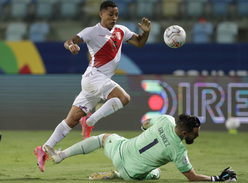 El mediocampista Yoshimar Yotún, izquierda de Perú, trata de evadir la barrida del guardameta Hernán Galíndez, de Ecuador, durante un partido por la Copa America, en el Estadio Olímpico de Goiania, Brasil, el miércoles 23 de junio de 2021. (AP Foto/Eraldo Peres)