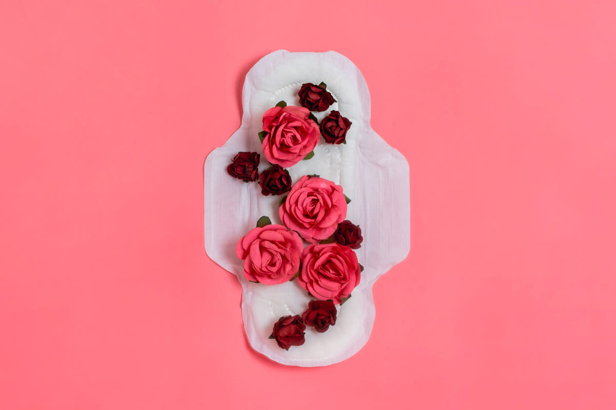 A pad is photographed from above with roses laying on top of it on a blush backdrop. 