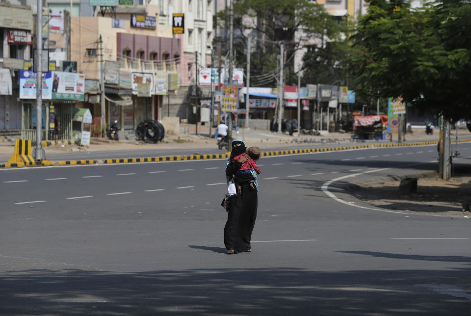 FILE - In this March 24, 2020, file photo, a Muslim woman carrying a child walks through a deserted street during a lockdown declared as a precautionary measure against COVID-19 in Hyderabad, India. Muslims in India are being stigmatized after the government blamed an Islamic missionary meeting for a surge in coronavirus cases. Experts who have studied previous epidemics warn that the stigma could hamper efforts to stop the contagion and prevent many from getting themselves tested. (AP Photo/Mahesh Kumar A, File)