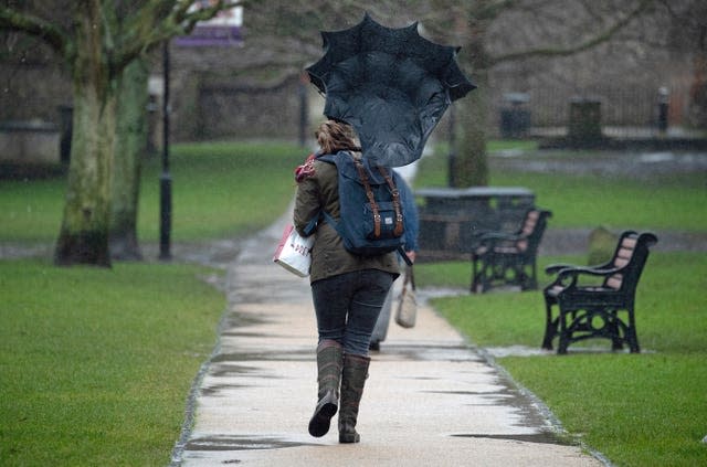 A gust of wind catches the umbrella of a person as they walk through the grounds of Winchester Cathedral in Winchester (Andrew Matthews/PA)