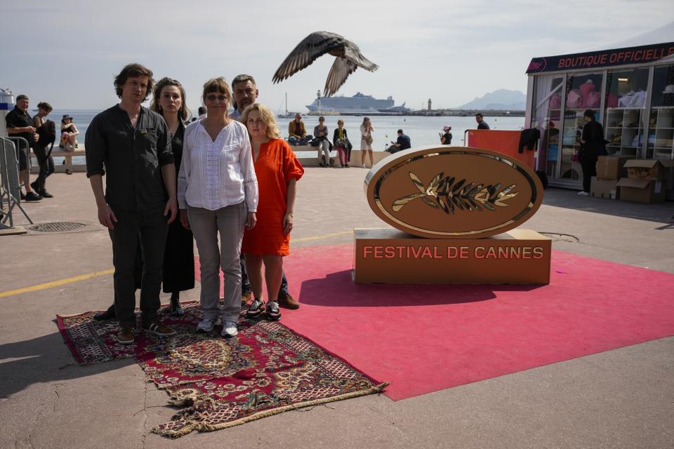 El equipo del documental "In the Rearview", Maciek Hamela, de izquierda a derecha, Kseniia Marchenko, Larysa Sosnovtseva, Yura Dunay y Anna Palenchuk en una alfombra originalmente dañada por una bomba en la ciudad de Lukashivka en Ucrania posa en el Boulevard de la Croisette en la 76a edición del Festival de Cine de Cannes en Cannes, en el sur de Francia, el 21 de mayo de 2023. (Foto AP/Daniel Cole)