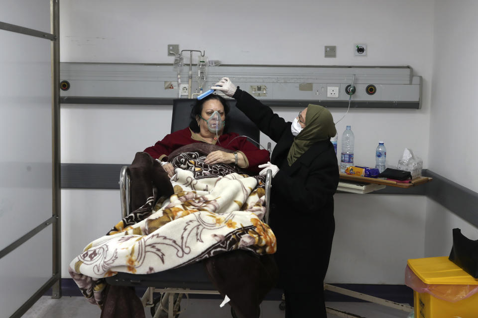 FILE - In this Friday, Jan. 22, 2021 file photo, a woman combs the hair of her sister, a COVID-19 patient, at the intensive care unit of the Rafik Hariri University Hospital in Beirut, Lebanon. As coronavirus vaccines trickle into some of the poorest countries in Asia, Africa and the Middle East, data suggest some women are consistently missing out, in another illustration of how the doses are being unevenly distributed around the world. (AP Photo/Bilal Hussein, file)