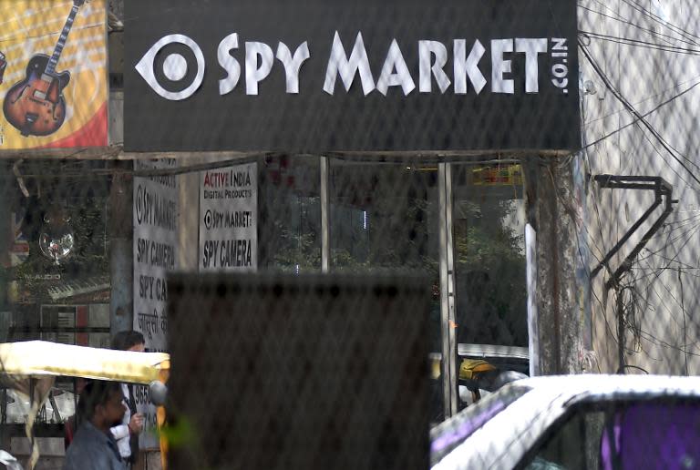 Indian commuters pass a shop dealing with 'spy equipment' in a market of New Delhi