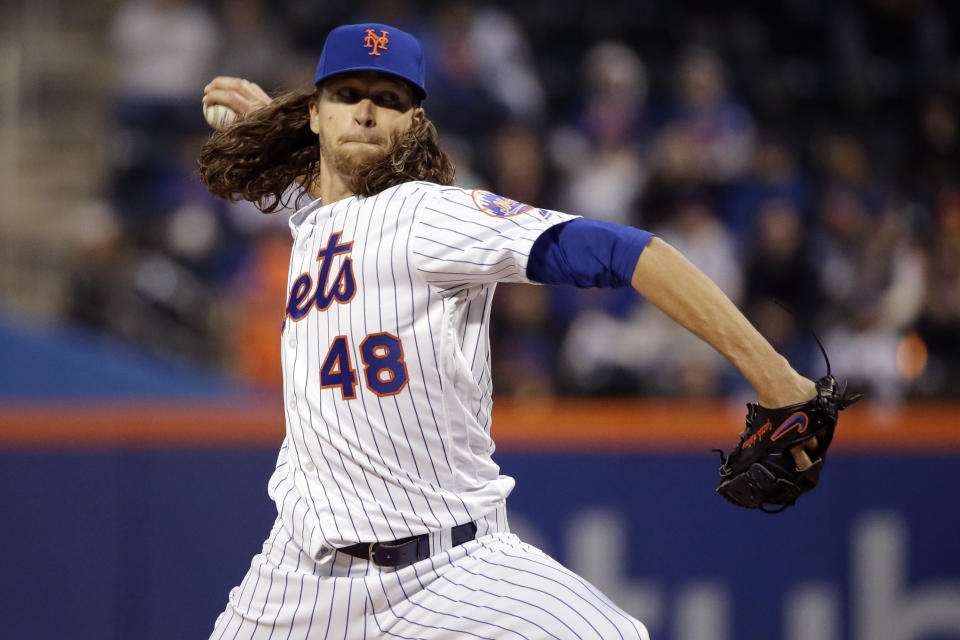 FILE - In this April 5, 2017, file photo, New York Mets starting pitcher Jacob deGrom throws during the first inning of the team's baseball game against the Atlanta Braves in New York. The scoreboard at Citi Field showed deGrom hitting 98 mph that night, and the ballpark buzzed with the Mets star right-hander seemingly back in top form. From watching broadcasts and scoreboards, fans are seeing velocities ramp up around the majors this year. Check the leaderboards at analytics website Fangraphs, and you’ll see that last April, pitchers averaged 92.2 mph on four-seam fastballs. Through Thursday’s games this season, they’re up to 93.1 mph, an unprecedented jump. Did some 300 pitchers all find ways to boost their speed in the offseason? Not quite. More likely, the perceived speed spike is coming from a change in how pitches are being recorded and reported. (AP Photo/Frank Franklin II, File)