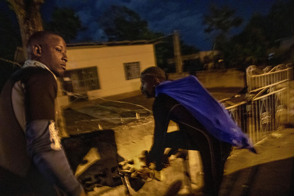 Nicholas Bingham, left, and Delroy Gooden, prepare to climb over a wall to go night spearfishing, which is banned, in Stewart Town, Jamaica, Friday, Feb. 15, 2019. Bingham and Gooden say they resort to illegal night spearfishing to make up for lost wages from the sanctuary's restrictions. Some fish and other sea creatures sleep in the reef at night making them easier to catch than during the day. (AP Photo/David Goldman)