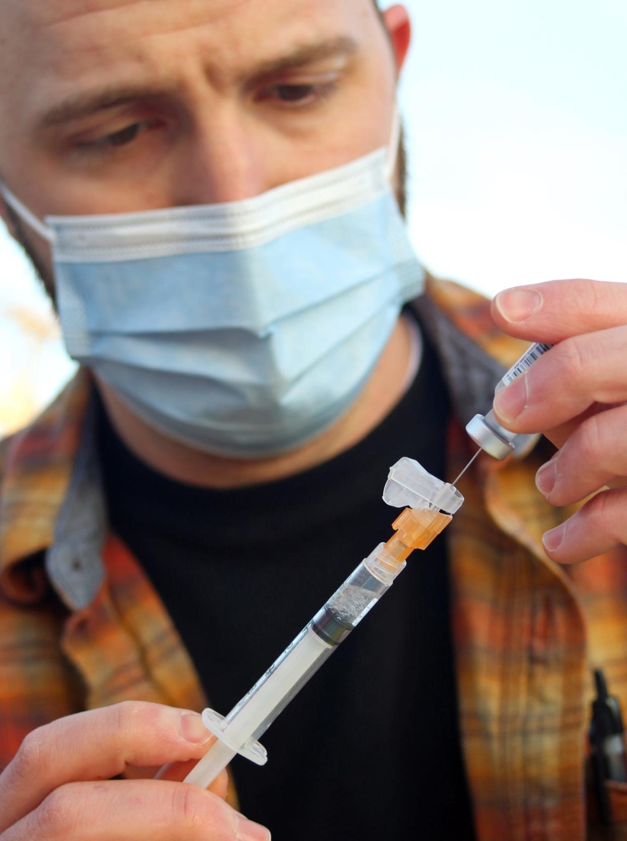 Pharmacist intern Graham Sprinkles prepares a dose of the Pfizer vaccine as free vaccination shots were offered in the parking lot of Mt. Zion Restoration Church on Crescent Lane in Gastonia early Thursday morning, Dec. 16, 2021.