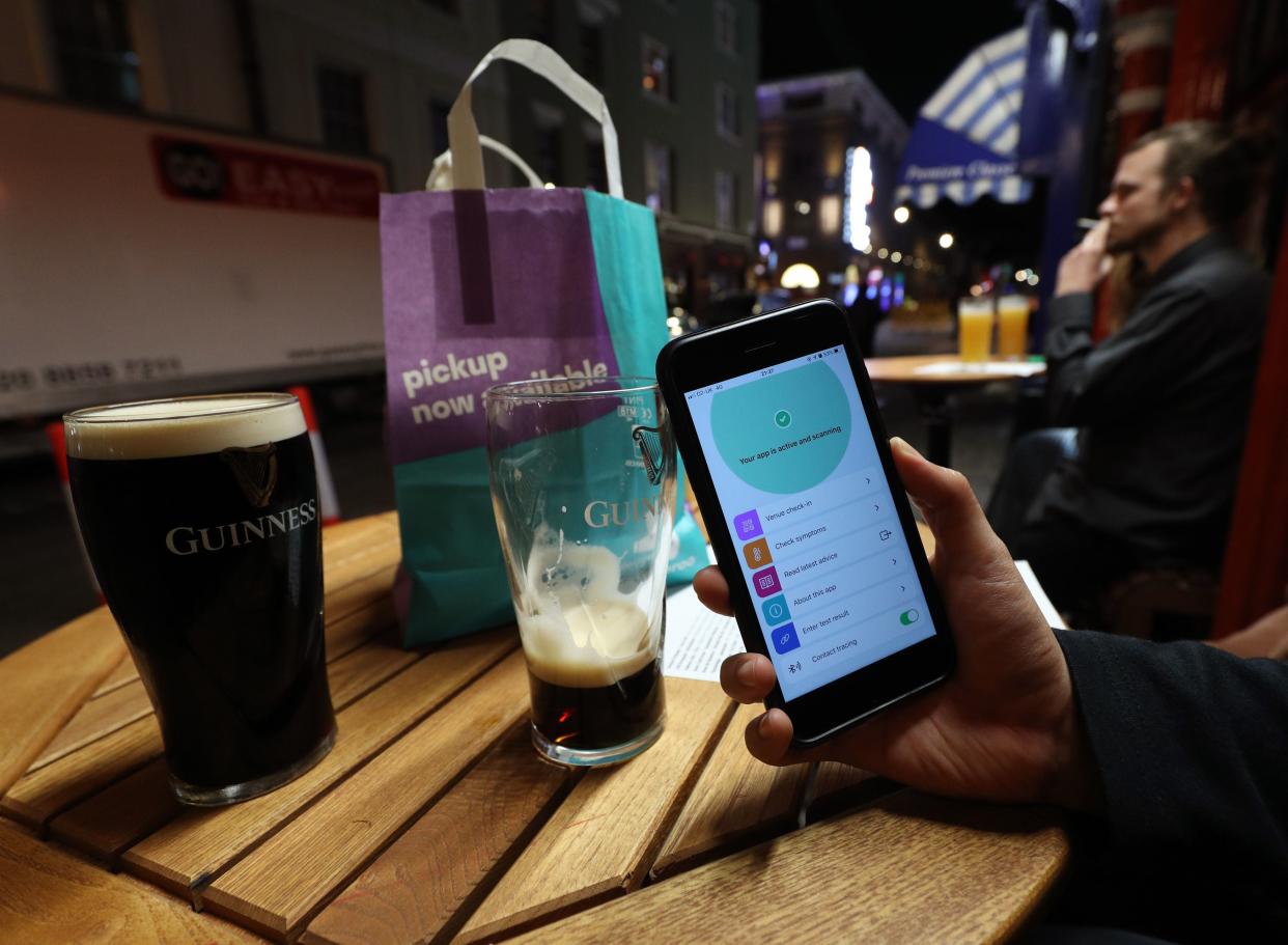 A person uses the NHS coronavirus contact tracing app outside The Coach and Horses pub in Soho, central London (PA)