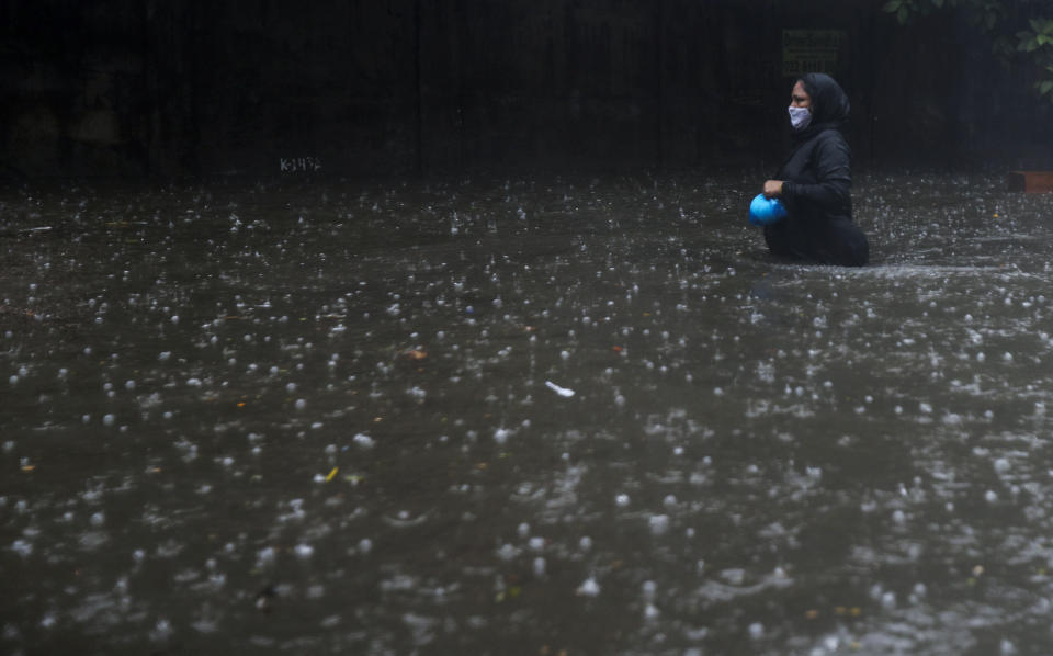 A woman wearing a mask walks through a waterlogged street in Mumbai, India, Monday, May 17, 2021. Cyclone Tauktae, roaring in the Arabian Sea was moving toward India's western coast on Monday as authorities tried to evacuate hundreds of thousands of people and suspended COVID-19 vaccinations in one state. (AP Photo/Rafiq Maqbool)