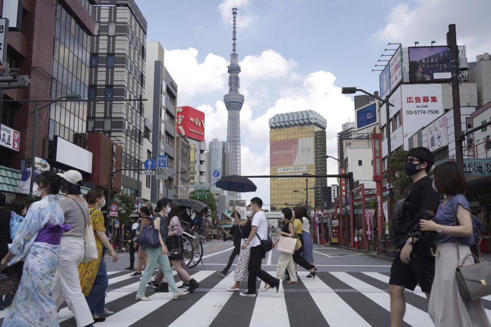 FILE - People walk along a pedestrian crossing in the tourist district of Asakusa, near the landmark Tokyo Skytree tower in Tokyo, Japan on Saturday, July 31, 2021. Japan will reopen its borders to foreign tourists June 10, 2022, but only to package tour participants for now, officials said Thursday, as the country starts to cautiously open its borders to foreign tourism for the first time in about two years. (AP Photo/Kantaro Komiya, File)