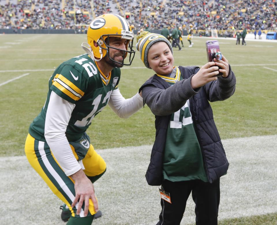 CORRECTS TO REMOVE SCORE- Simon McPhail takes a selfie with Green Bay Packers' Aaron Rodgers before an NFL football game against the Detroit Lions Sunday, Dec. 30, 2018, in Green Bay, Wis. (AP Photo/Mike Roemer)