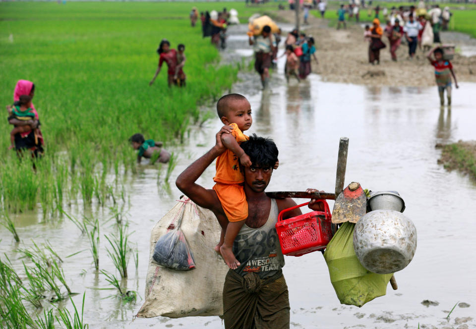 A Rohingya refugee carries a child through a paddy field after crossing the Bangladesh-Myanmar border, in Teknaf, Bangladesh, on Sept. 6, 2017.
