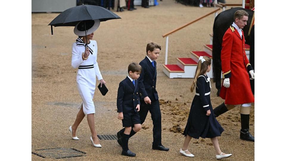 Princess Kate shelters from the rain with an umbrella as she walks with her children back to the Glass State Coach at Horse Guards Parade during Trooping the Colour