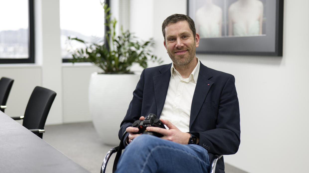  Leica SL System product manager, Steffen Rau, sat at a desk holding a Leica SL3. 