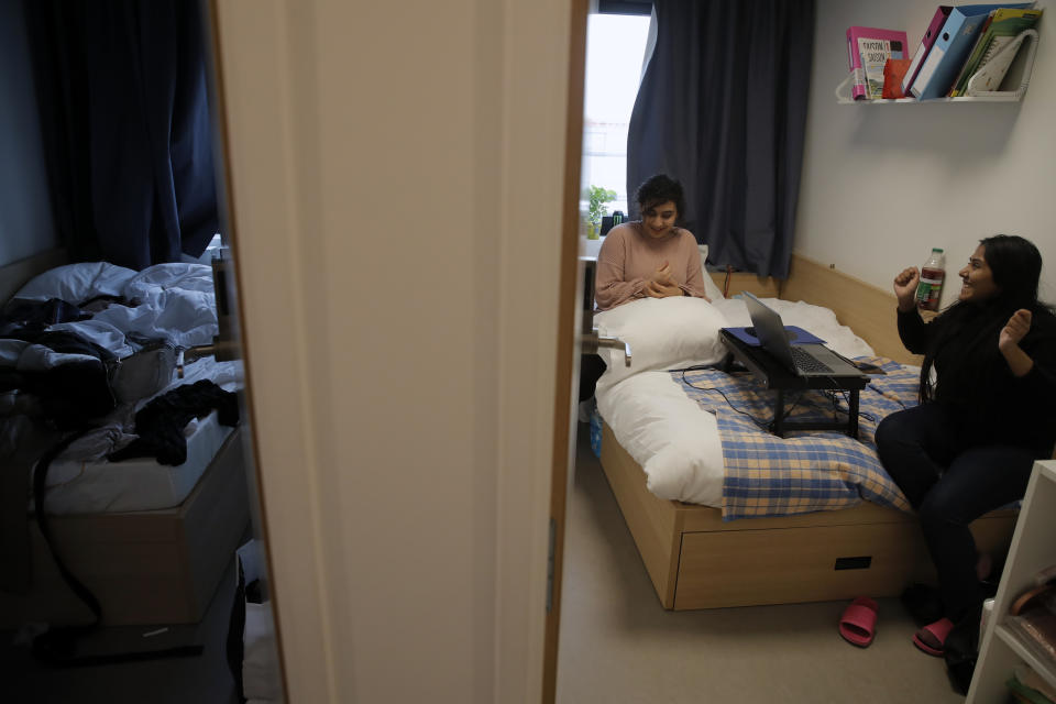 Nouhaila Fakhor from Morocco, a student of commerce, left, and Indian Prajakta Prakash Tamhankar, a student in international business, speak in her student housing in Ivry sur Seine, outside Paris, Thursday, Feb. 11, 2021. (AP Photo/Christophe Ena)