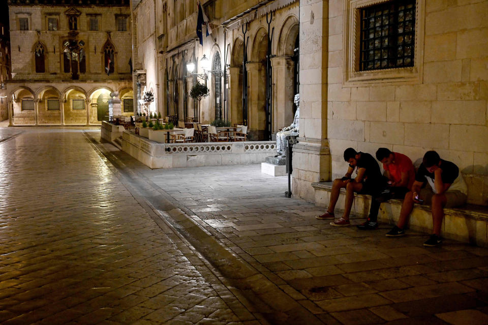 Image: Three youths looking at their mobile phones on empty street in the old town of the southern Croatian city of Dubrovnik, as the country eases lockdown measures taken to curb the spread of the COVID-19 pandemic (Denis Lovrovic / AFP - Getty Images)