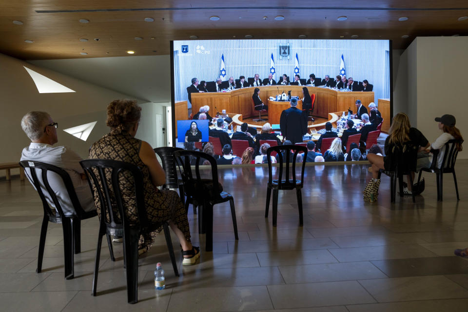 Israelis watch a live broadcast of Israel's Supreme Court justices as they hear deliberations in the first case challenging Prime Minister Benjamin Netanyahu's judicial overhaul in Tel Aviv, Israel, Tuesday, Sept. 12, 2023. The contentious plan has triggered months of mass protests and bitterly divided the country. (AP Photo/Oded Balilty)