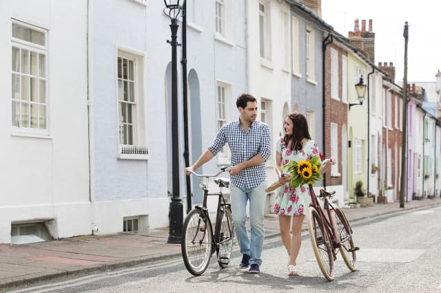 A couple walking with bicycles and flowers