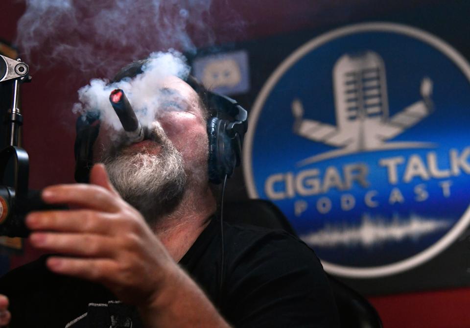 Rob Jones puffs out a large cloud after lighting a new cigar during an episode of 'The Cigar Talk."