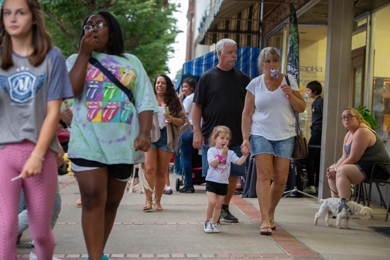 Penny Butler and her graddaughter Cate Bryan, 2, walk along West 7th Street with Mark Lewis during a First Fridays event in Columbia, Tenn, on Friday, Aug. 8, 2021.
