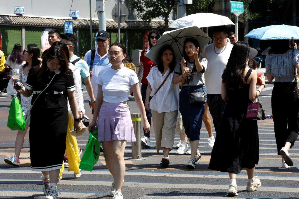 People walk on a street amid an orange alert for heatwave in Beijing, China June 22, 2023. REUTERS/Tingshu Wang