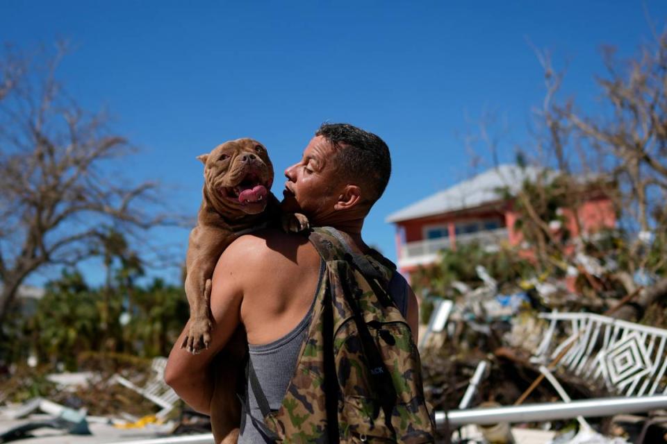 Eduardo Tocuya carga a un perro, el viernes 30 de septiembre de 2022, que recuperó con la esperanza de reunirlo con sus dueños, dos días después del paso del huracán Ian, en Fort Myers Beach, Florida. Rebecca Blackwell/AP