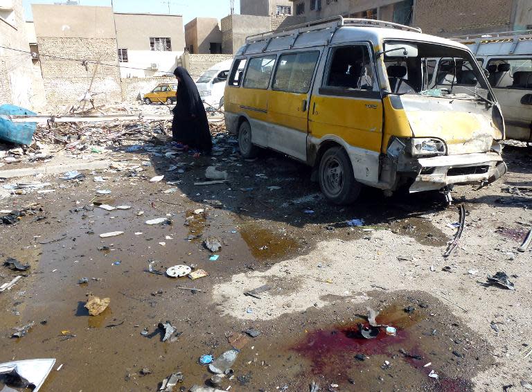 A woman walks across the debris following an explosion at a bus centre in the the Mashtal district of the capital Baghdad on October 27, 2013, as nine car bombs exploded in Shiite-majority areas of Baghdad province killing at least 30 people