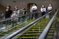 People wearing face masks to protect against the coronavirus ride escalators at a shopping mall in Beijing, Friday, Aug. 14, 2020. China's factory output rose just under 5% last month from a year earlier while retail sales fell slightly, suggesting the country's recovery from the coronavirus pandemic remains muted. (AP Photo/Mark Schiefelbein)