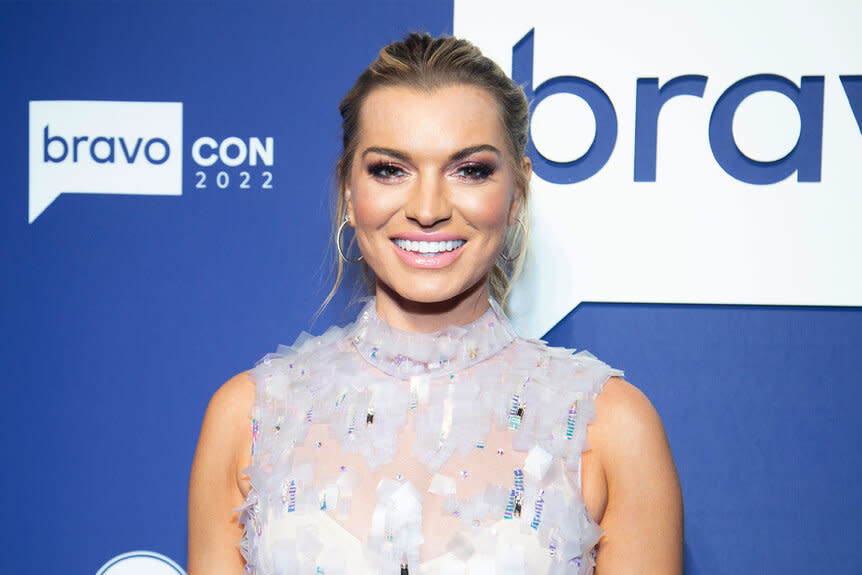 Lindsay smiling in a gown in front of the BravoCon 2022 step and repeat.