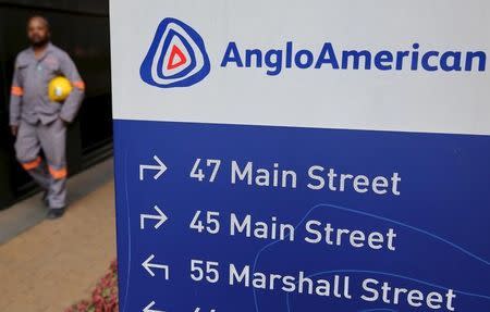 A worker walks past a board outside Anglo American offices in Johannesburg, August 21, 2015. REUTERS/Siphiwe Sibeko