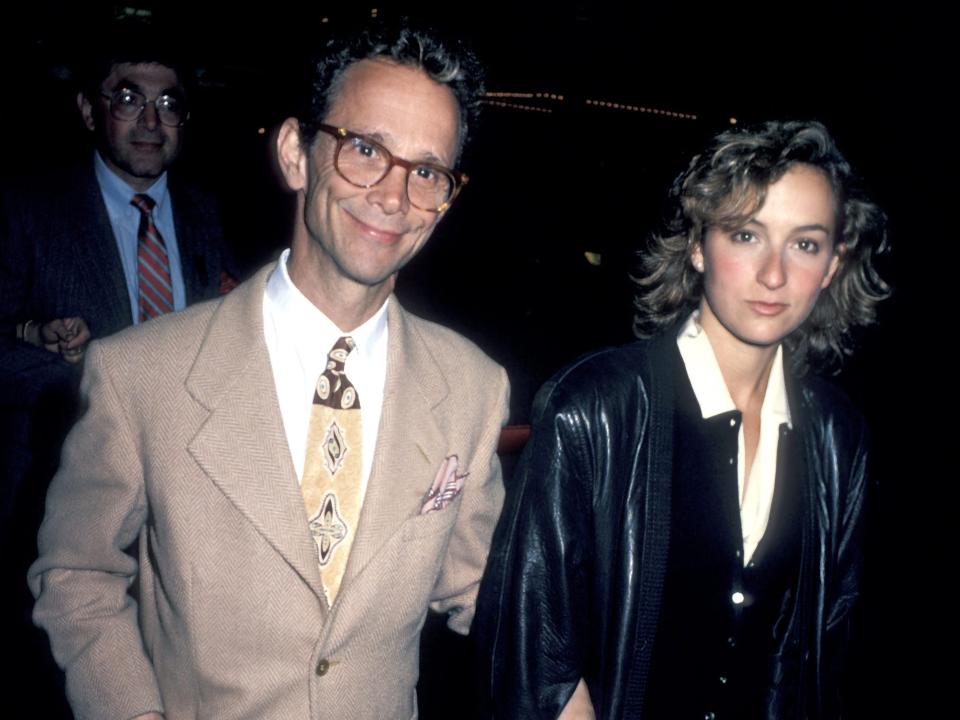 Jennifer with a stern face outside wearing a collared shirt and leather jacket.