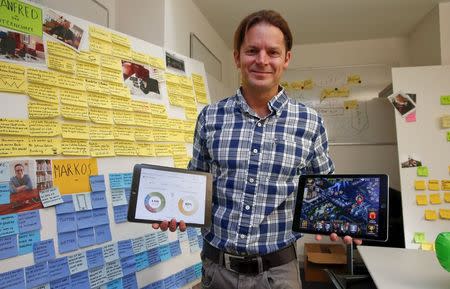 Dave Bruno, head of the innovation lab at Swiss bank UBS, poses with two tablet computers in his office in Zurich January 16, 2015. REUTERS/Arnd Wiegmann/Files