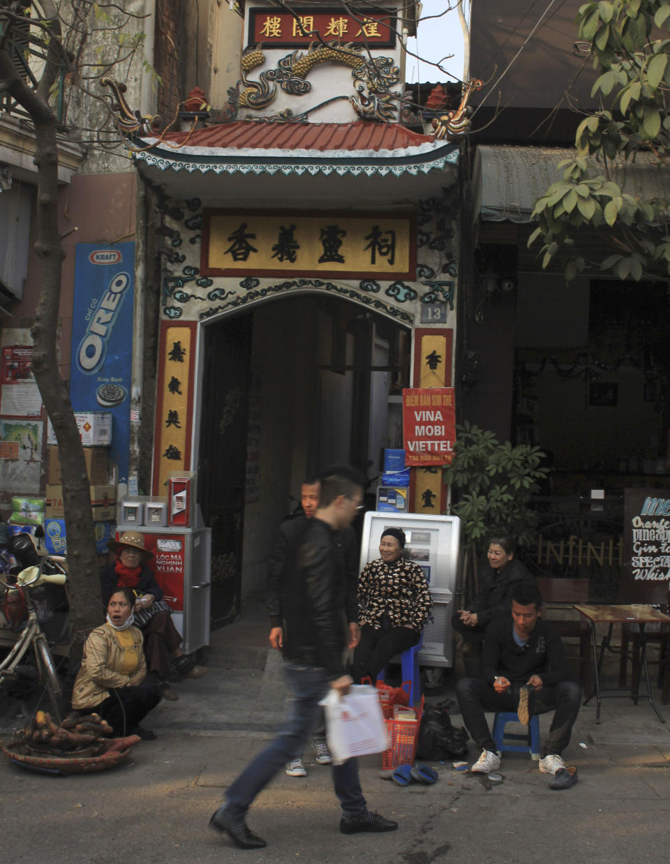 In this Jan. 23, 2014 photo, a man walks by Huong Nghia Temple in the heart of the Old Quarter of Hanoi, Vietnam. With property values high, this neighborhood could change dramatically in the coming years as similar ones already have in Singapore, Shanghai and many other cities. Authorities want to begin gentrifying the Old Quarter by relocating 6,200 households between 2014 and 2020. New construction is likely a few years away, but a few hundred residents already have been relocated. (AP Photo/Mike Ives)