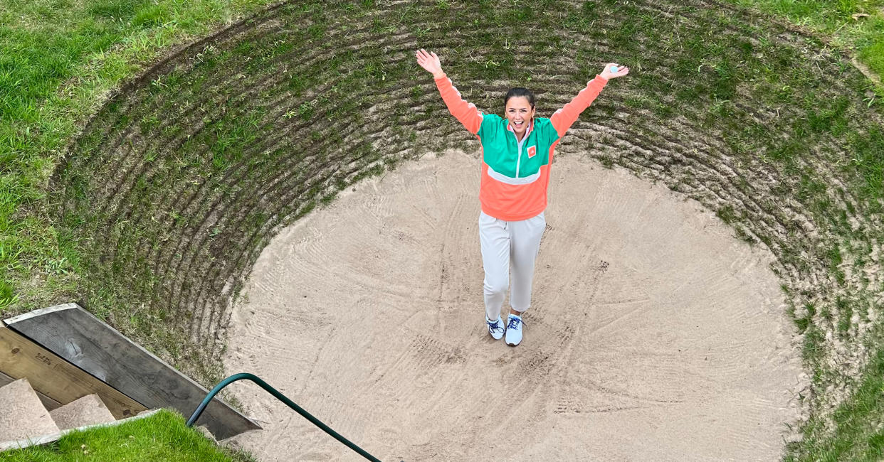  Female golfer with her hands up posing in a bunker 