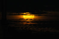 A full 'Super moon', partially obscured by clouds, is seen rising in Outback Australia on April 08, 2020 in Louth, Australia. Officially known as the perigee-syzygy Moon, the 'super pink moon' is the largest full moon for 2020. The annual phenomenon occurs when the full moon is directly opposite the sun and also at the closest point to earth in its orbit. (Photo by Jenny Evans/Getty Images)