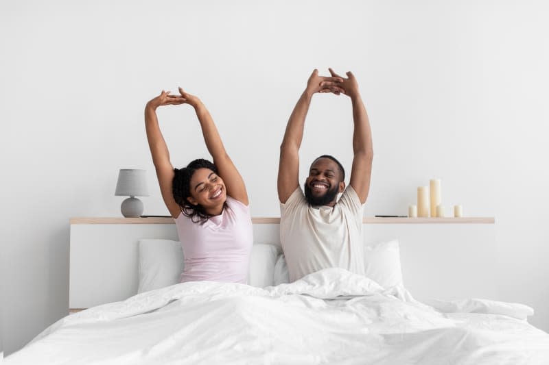 Couple in bed together stretching