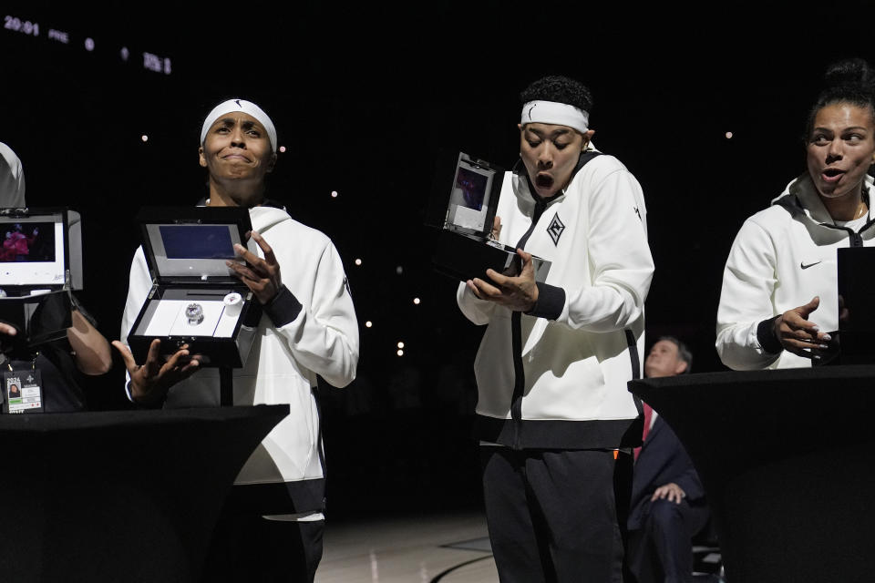 From left, Las Vegas Aces guard Sydney Colson, guard Kierstan Bell and forward Alysha Clark react as they open boxes with their 2023 championship rings before a WNBA basketball game Tuesday, May 14, 2024, in Las Vegas. (AP Photo/John Locher)