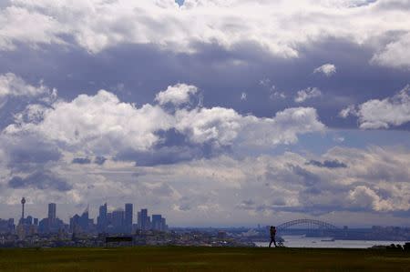 A storm approaches as a man carries his son while walking in a park overlooking the central business district (CBD) of Sydney, Australia, September 29, 2016. REUTERS/David Gray