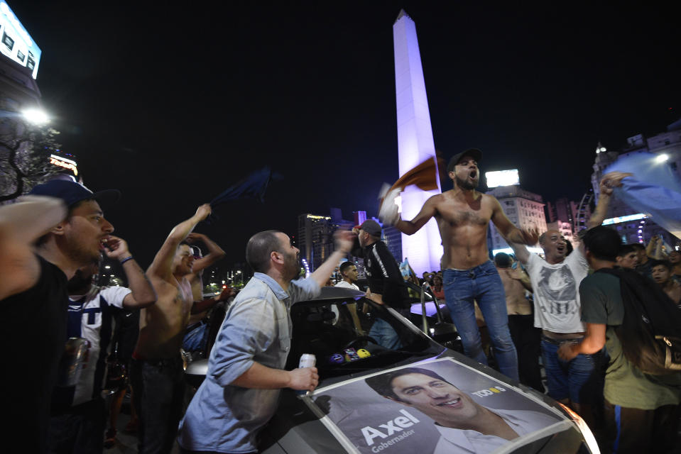 Supporters of Peronist presidential candidate Alberto Fernández and running mate, former President Cristina Fernández, celebrate after incumbent President Mauricio Macri conceded defeat at the end of election day at the Obelisco in Buenos Aires, Argentina, Sunday, Oct. 27, 2019. In the poster is Axel Kicillof, who won the governor's election for Buenos Aires province. (AP Photo/Gustavo Garello)