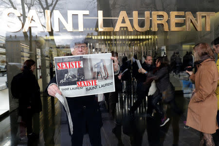 Activists hold placards which read "Sexist" during a demonstration in front of a Yves Saint Laurent shop in Paris, France, March 7, 2017. REUTERS/Philippe Wojazer