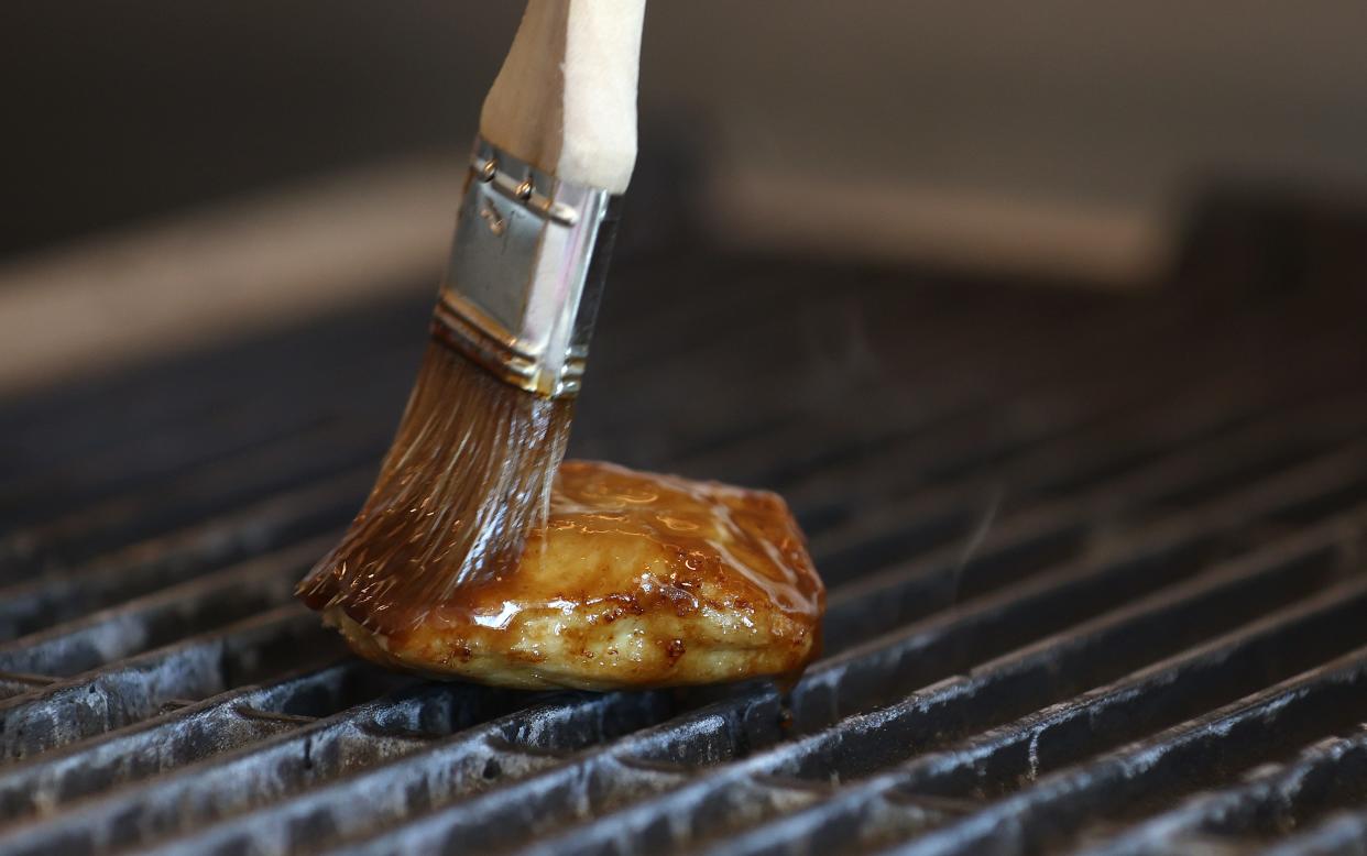 Chef Zach Tyndall brushes sauce on a piece of Good Meat's lab-grown chicken as it cooks on a grill at the Eat Just office on July 27, 2023 in Alameda, California.