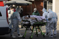 An elderly man on a stretcher is wheeled into the fever clinic at a hospital in Beijing, Friday, Dec. 9, 2022. China began implementing a more relaxed version of its strict "zero COVID" policy on Thursday amid steps to restore normal life, but also trepidation over a possible broader outbreak once controls are eased. (AP Photo/Ng Han Guan)