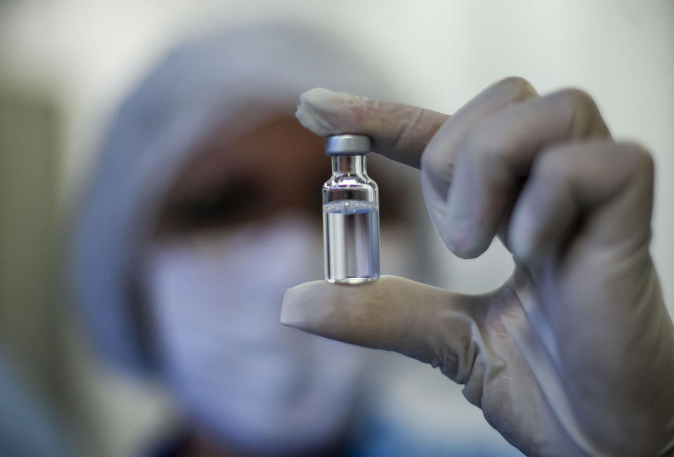 A worker shows a vial of the AstraZeneca vaccine for COVID-19 produced by the Fiocruz Foundation in Rio de Janeiro, Brazil, Friday, Feb. 12, 2021. (AP Photo/Bruna Prado)