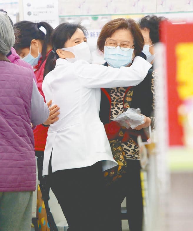 北市南京東路躍獅京東藥局的藥師鍾嘉芬（左），在開賣口罩前即忙東忙西幫排隊客人服務，一位排數小時的老顧客在開賣後迅速買到口罩，兩人高興得互相擁抱。（鄭任南攝）