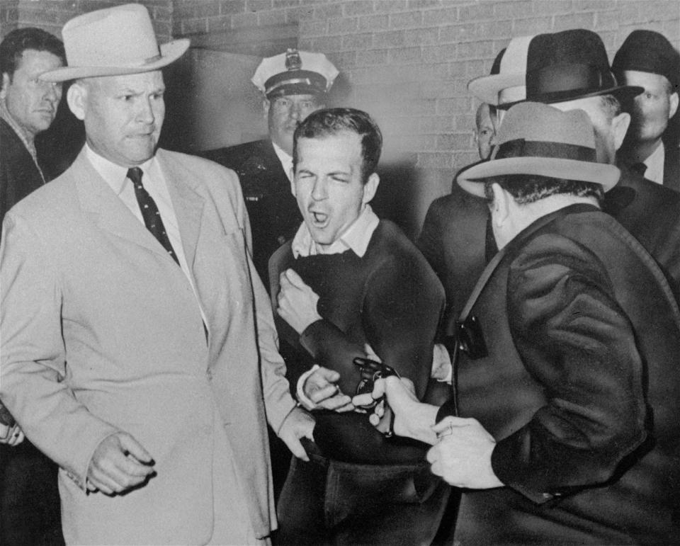 <p>Lee Harvey Oswald, assassin of President John F. Kennedy, reacts as Dallas night club owner Jack Ruby, foreground, shoots at him from point blank range in a corridor of Dallas police headquarters, Nov. 24, 1963. At left is Detective Jim Leavelle. Leavelle wanted to secretly take Oswald out the side door of Dallas police headquarters. His boss wanted to keep a promise to reporters. So Leavelle handcuffed himself to President Kennedy’s assasin, stepped into a crowded basement and became an accidental part of history. (Photo: Dallas Times-Herald, Bob Jackson/AP) </p>