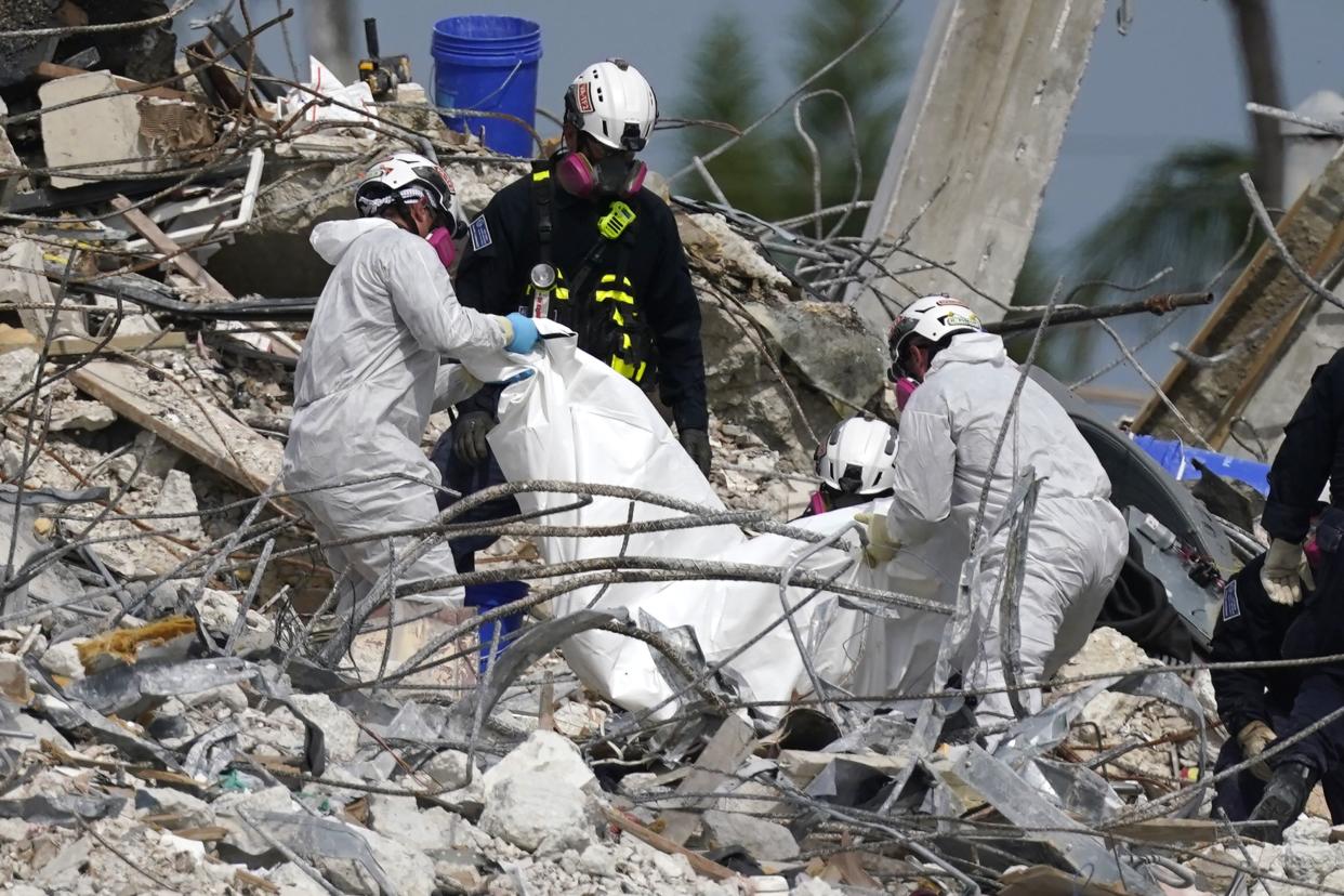 Rescue workers lift a tarp containing recovered remains at the site of the collapsed Champlain Towers South condo building, Monday, July 5, 2021, in Surfside, Fla. The remaining structure was demolished Sunday, which partially collapsed on June 24. Many people remain unaccounted for.