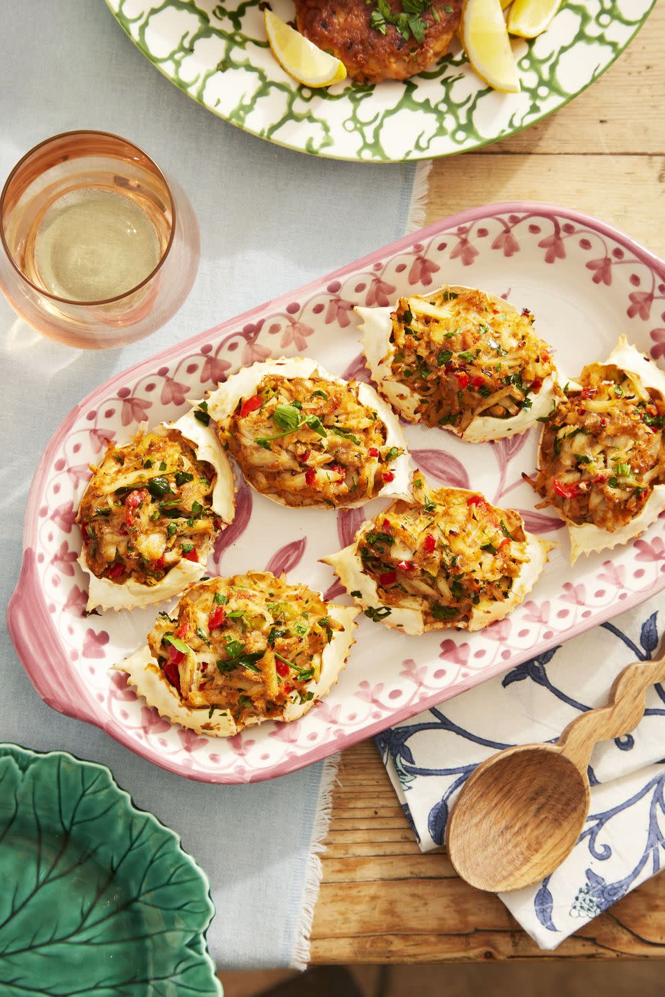 baked deviled crab arranged on an pinkish red patterned oval serving dish